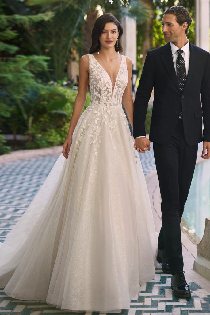Vestido de noiva romântico estilo princesa, confeccionado em tule, renda e pedraria com decote em V e costas em V.