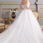 Vestido rodado (Branco), decote V. Saia em organza sobreposta por tule paetezado, camada de tule liso com aplicações de renda fio de seda e barrado de crinol. Corpo transparente com aplicações de renda fio de seda, bordado por madrepérolas, pérolas e miçangas. Costas em decote V com trançado.